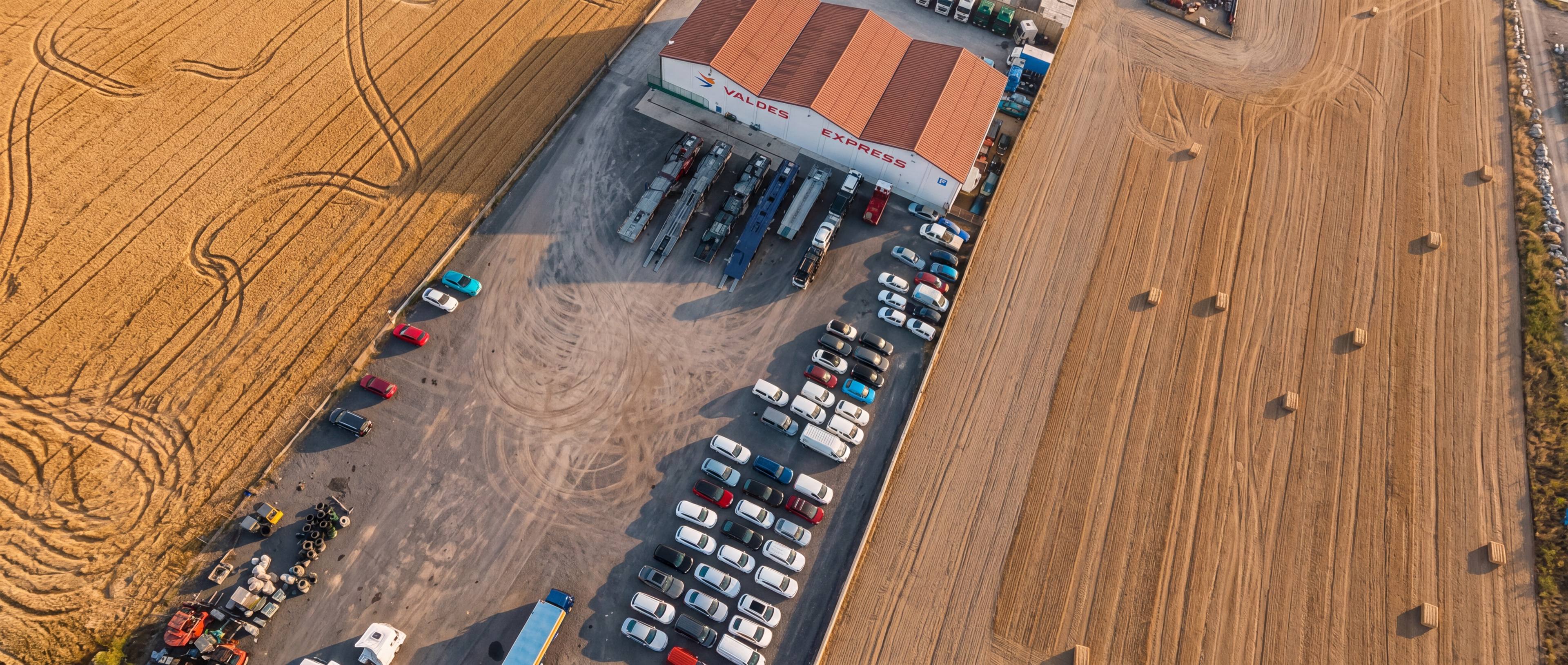 La campa de Valdés Express en Vitoria desde el aire, con la nave, los remolques y los coches aparcados entre campos de cereal