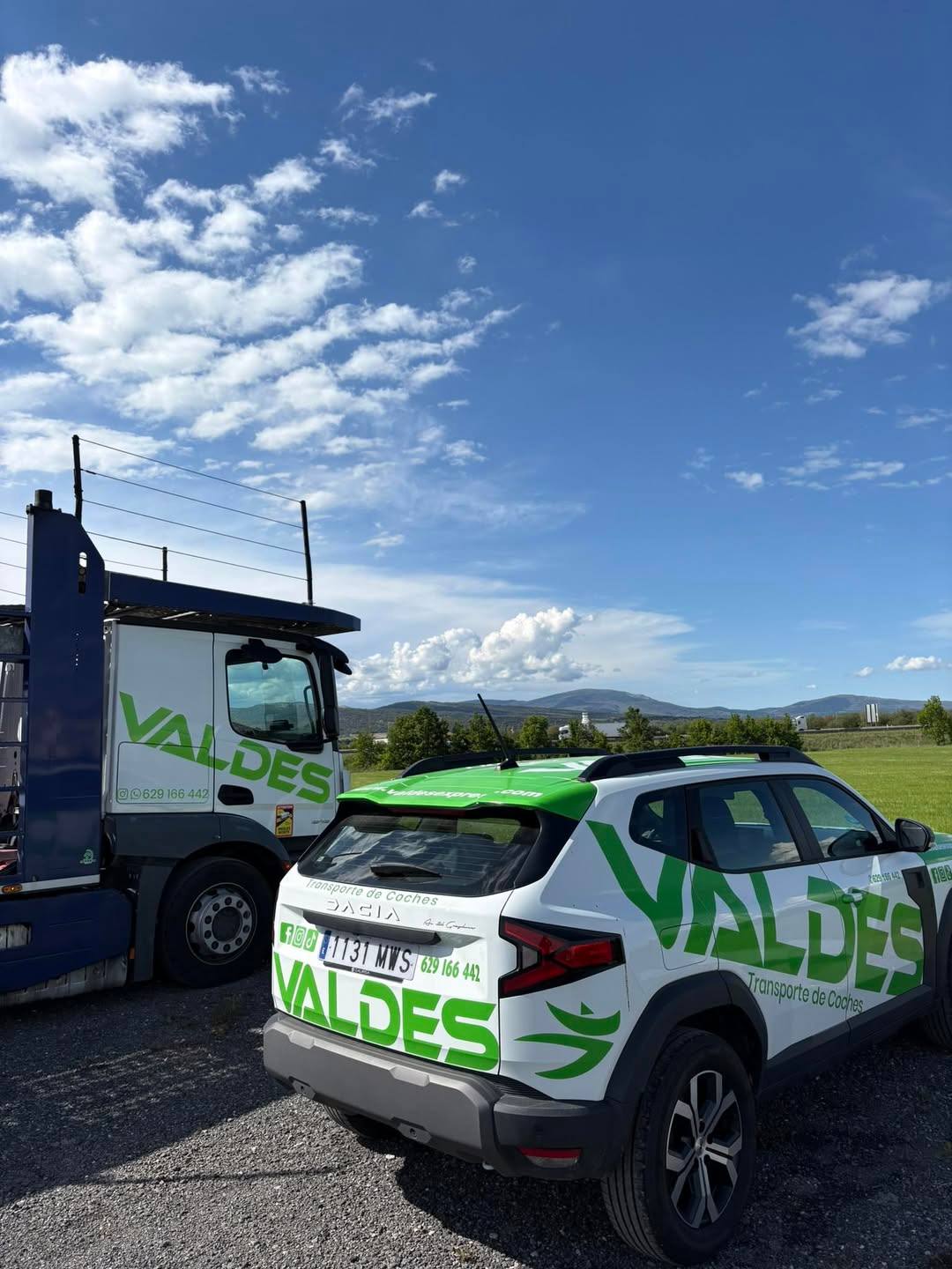 Coche rotulado de Valdés Express junto a un camión portavehículos
