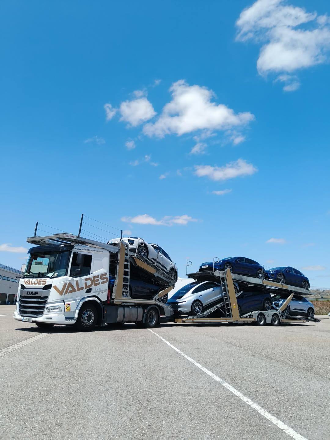 Camión DAF de Valdés Express con el remolque portavehículos cargado, bajo un cielo azul