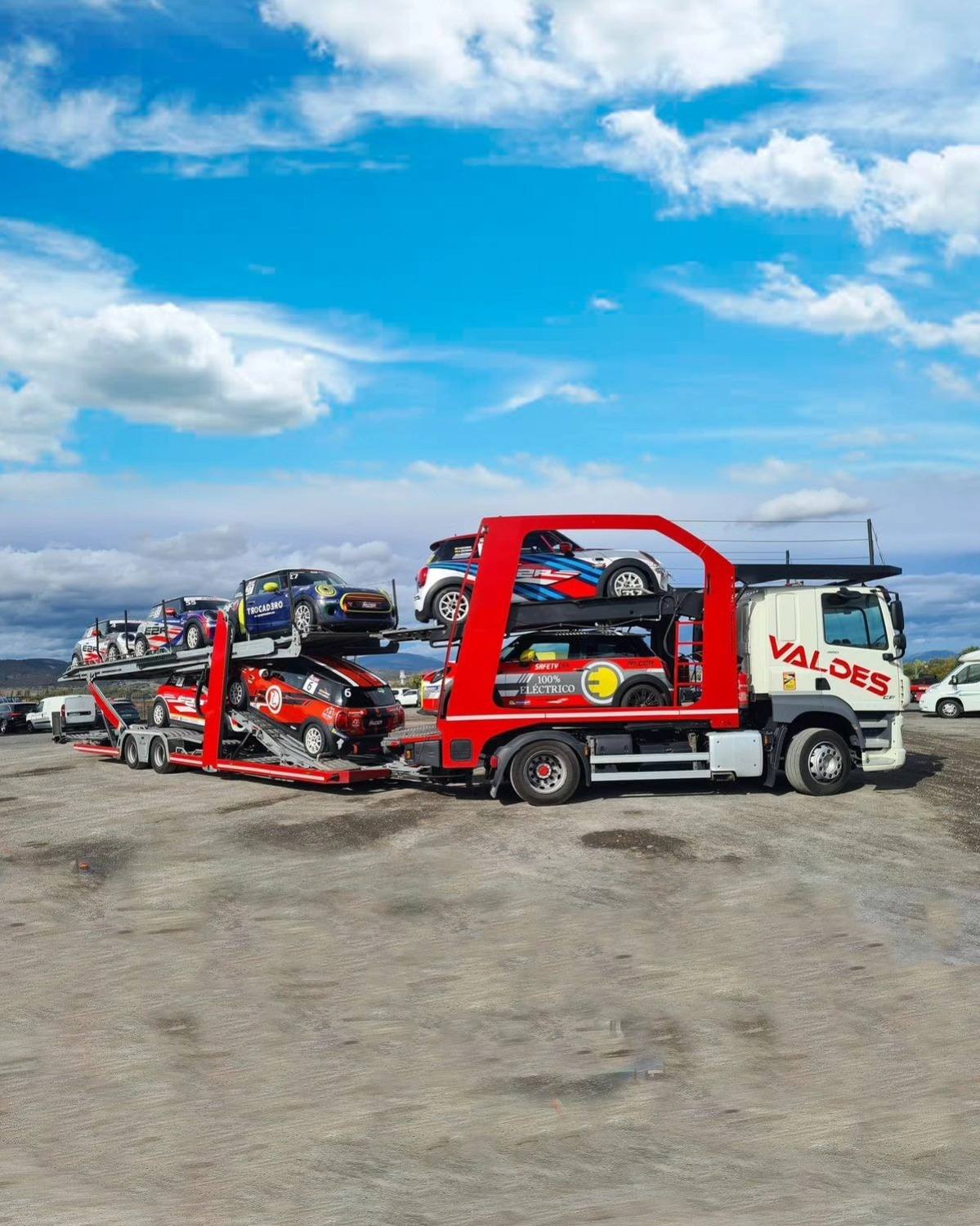 Camión portavehículos rojo de Valdés Express cargado de coches en la campa