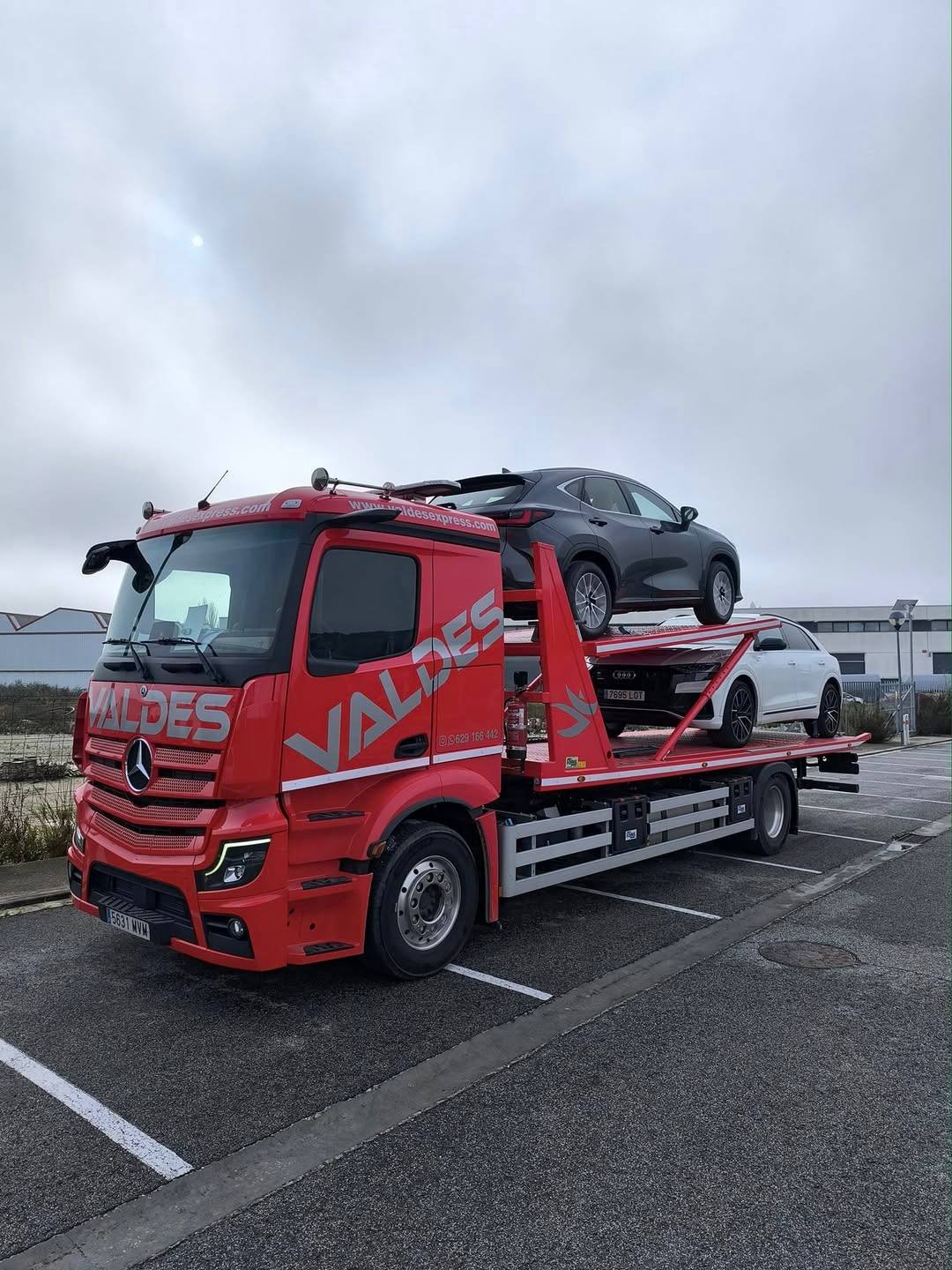 Camión Mercedes rojo de Valdés Express con dos coches cargados en la plataforma