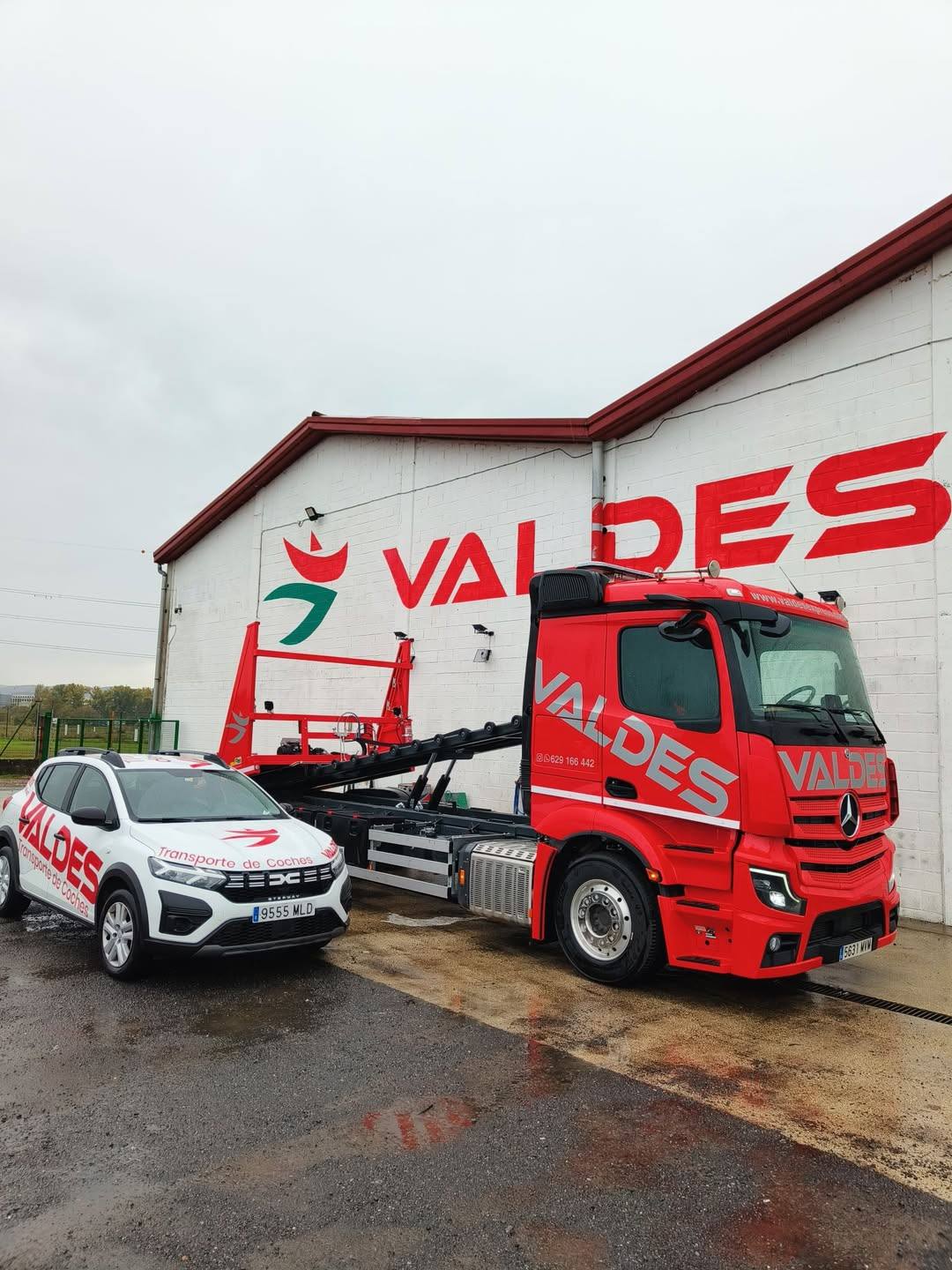 Camión rojo de Valdés Express y un coche rotulado delante de la nave con el logotipo de Valdés